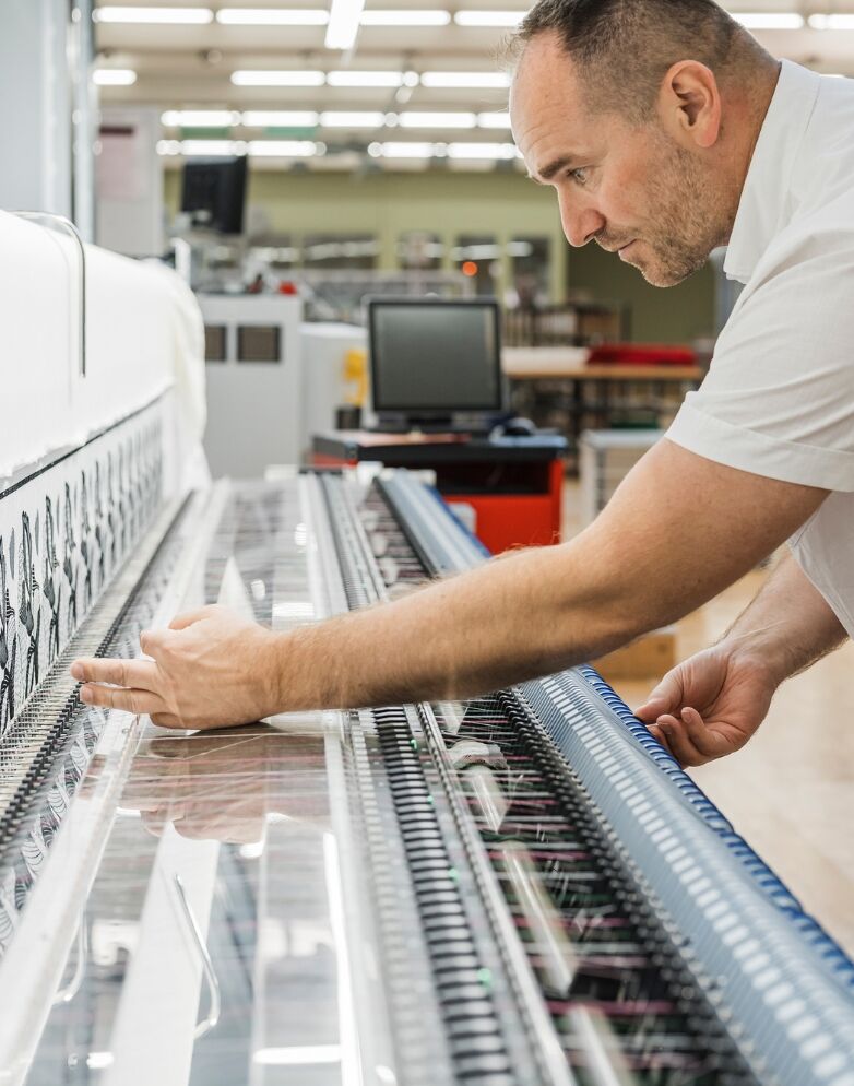 Mitarbeiter richtet eine Stickmaschine ein
